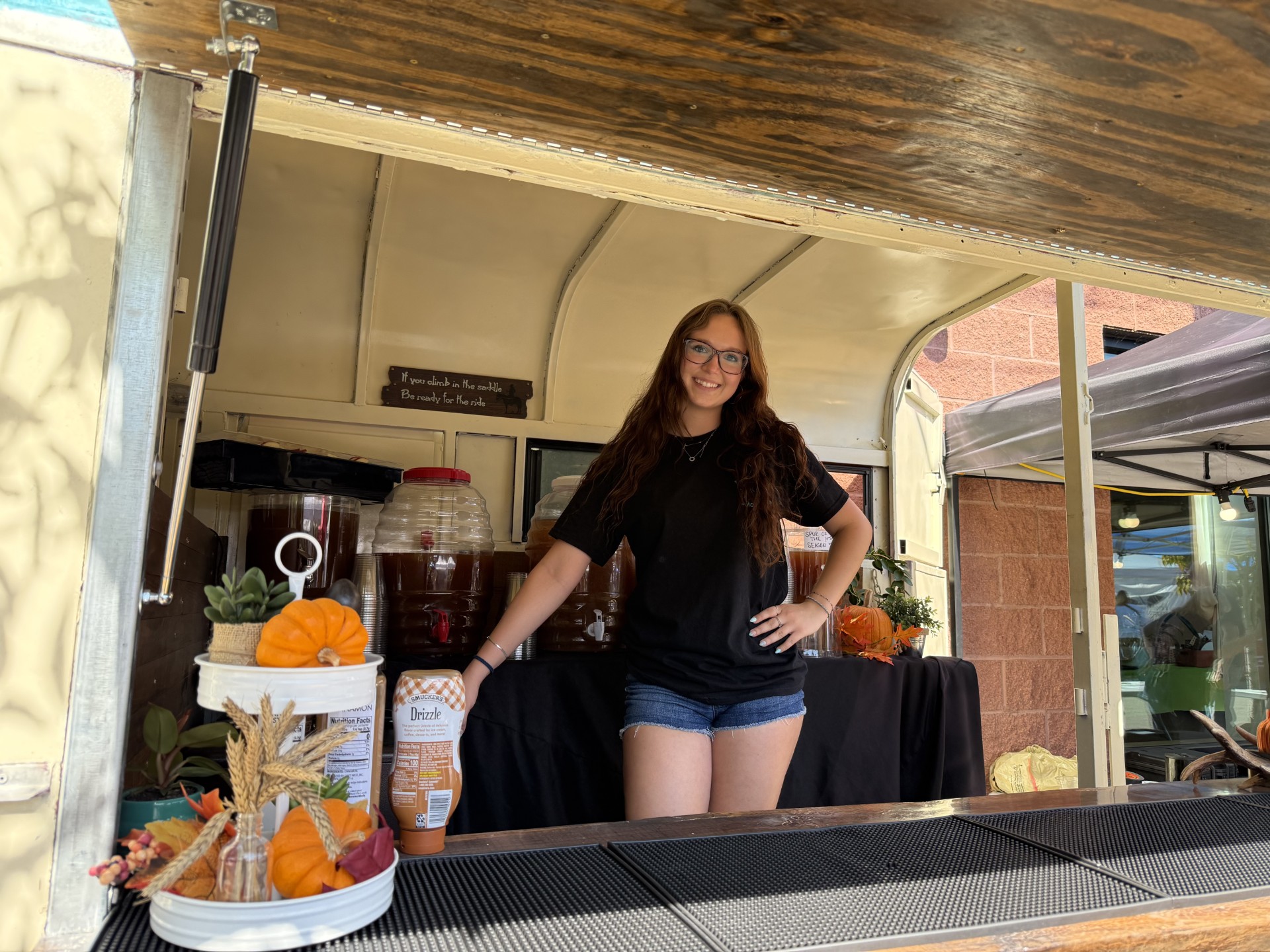 Hannah Beyer smiling from inside The Rusty Spur trailer bar, ready to serve